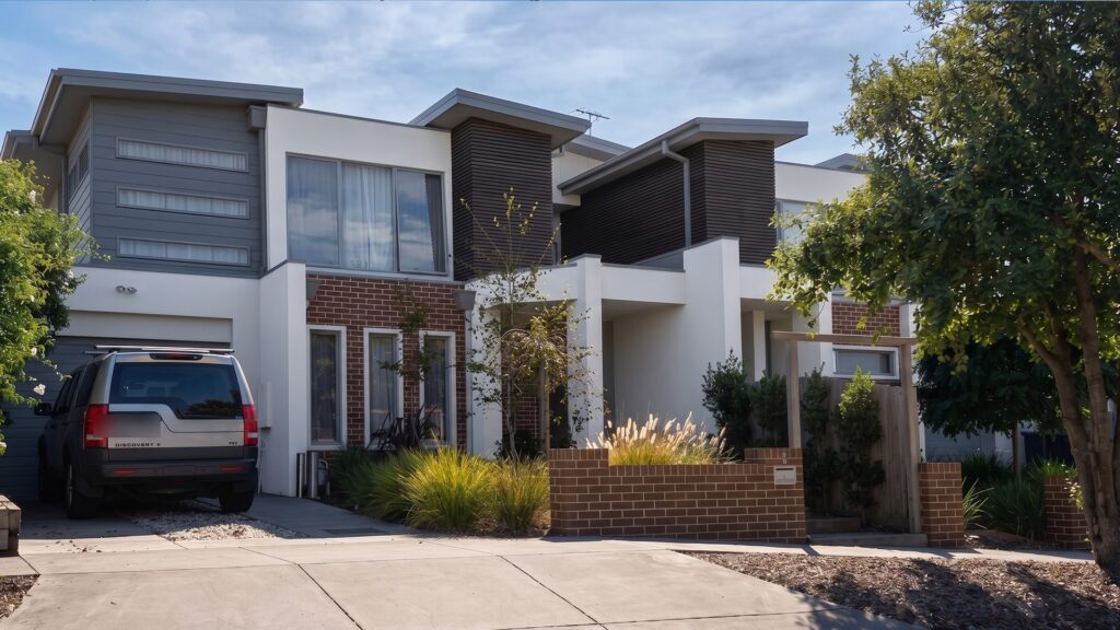 Street view of two double storey townhouses in Chelsea with grey cladding and brick facades